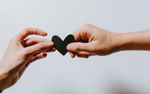 Two hands holding either end of a paper heart