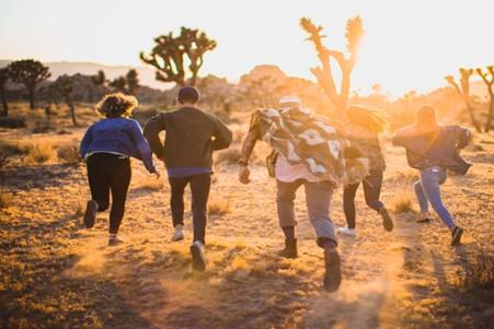 View of young peoples backs as they run into the sunset