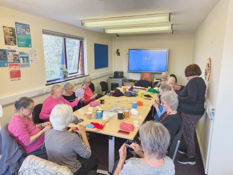 A group seated around a table knitting