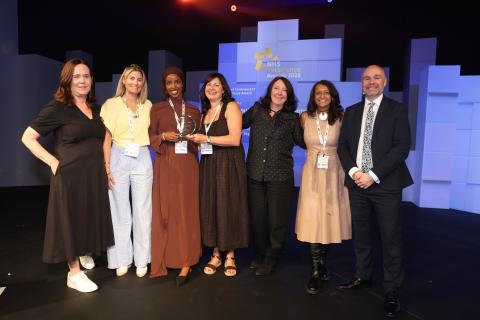 Group of people (6 female, one male) accepting an award. 